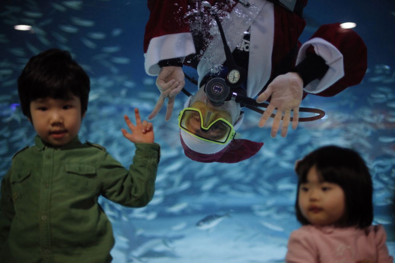 A diver dressed as Santa Claus poses for a photograph with children during a promotional event for the "Sardines Feeding Show with Santa Claus" at the Coex Aquarium in Seoul, South Korea, on December 11.