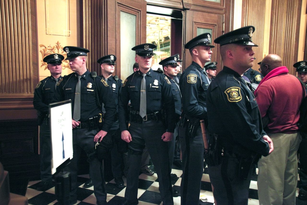Michigan State Police guard the entrance to the House chamber as protestors fill the building.