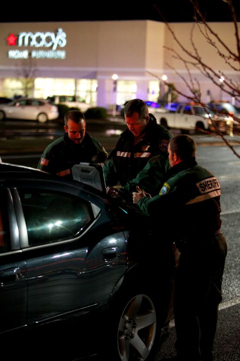 Lt. James Rhodes of the Clackamas County Sheriff's Office works with other responders in the parking lot of the mall.