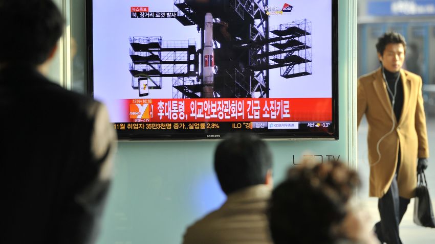 Travellers watch a TV screen broadcasting news on North Korea's rocket launch, at a railway station in Seoul on December 12, 2012.