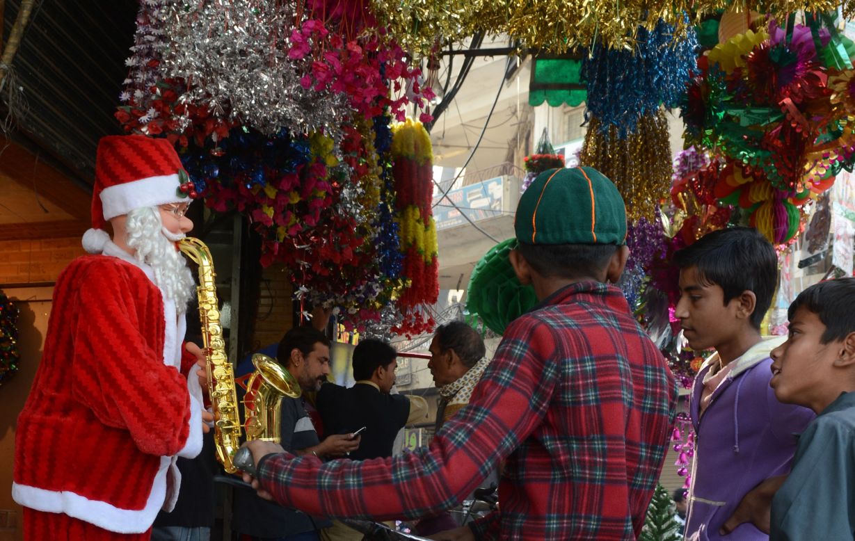 Pakistani children check out a sax-playing Santa Claus outside a shop in Lahore on December 9. 