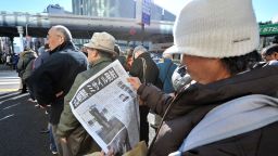 A woman reads an extra edition newspaper reporting the rocket launch by North Korea, along a street in downtown Tokyo on December 12, 2012.