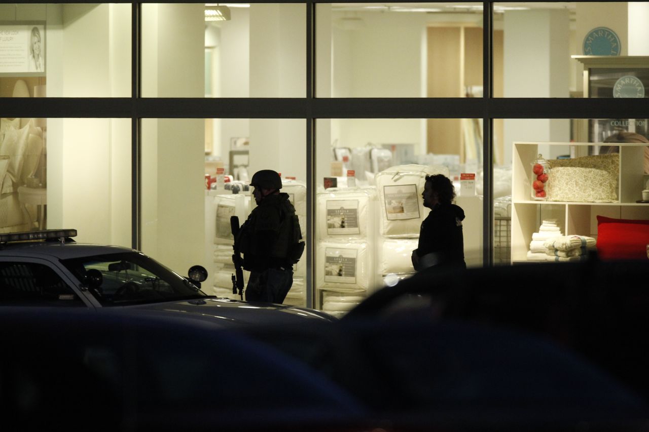 Two people walk in front of the lit windows of the mall on Tuesday night.