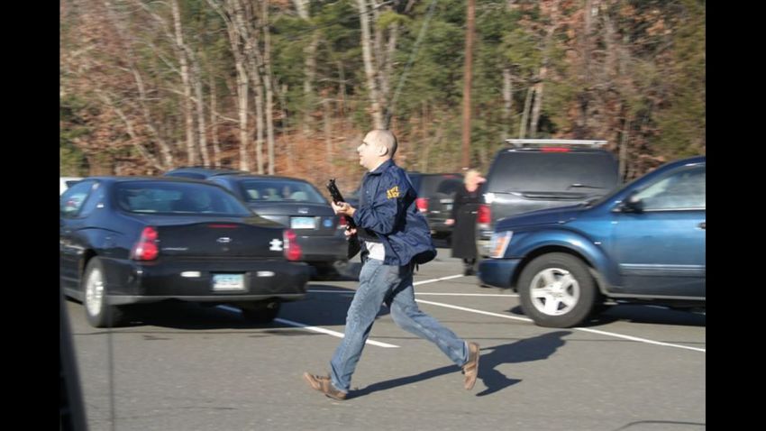 A Connecticut State Police officer runs with a shotgun at the Sandy Hook Elementary School in Newtown on Friday, December 14.