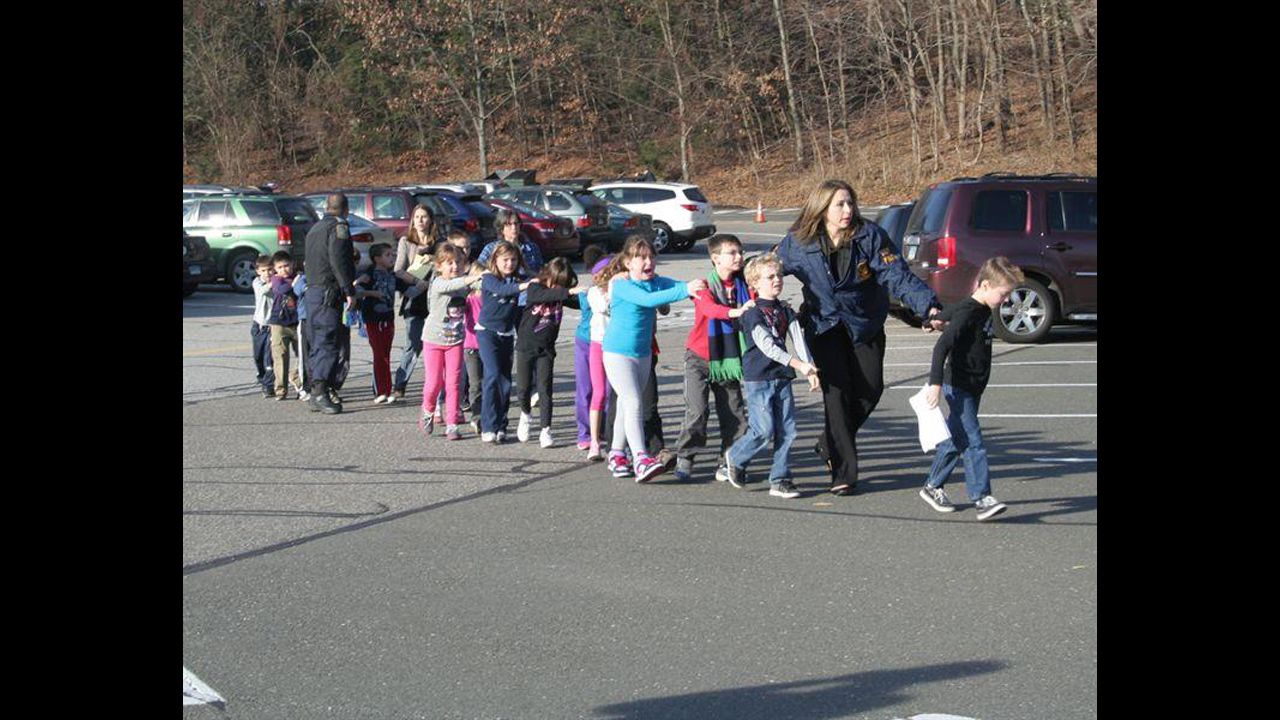 <strong>December 14: </strong>State police personnel lead children away from Sandy Hook Elementary School in Newtown, Connecticut. A gunman killed 18 children and six adults at the school before he died; two more children died later at a hospital.