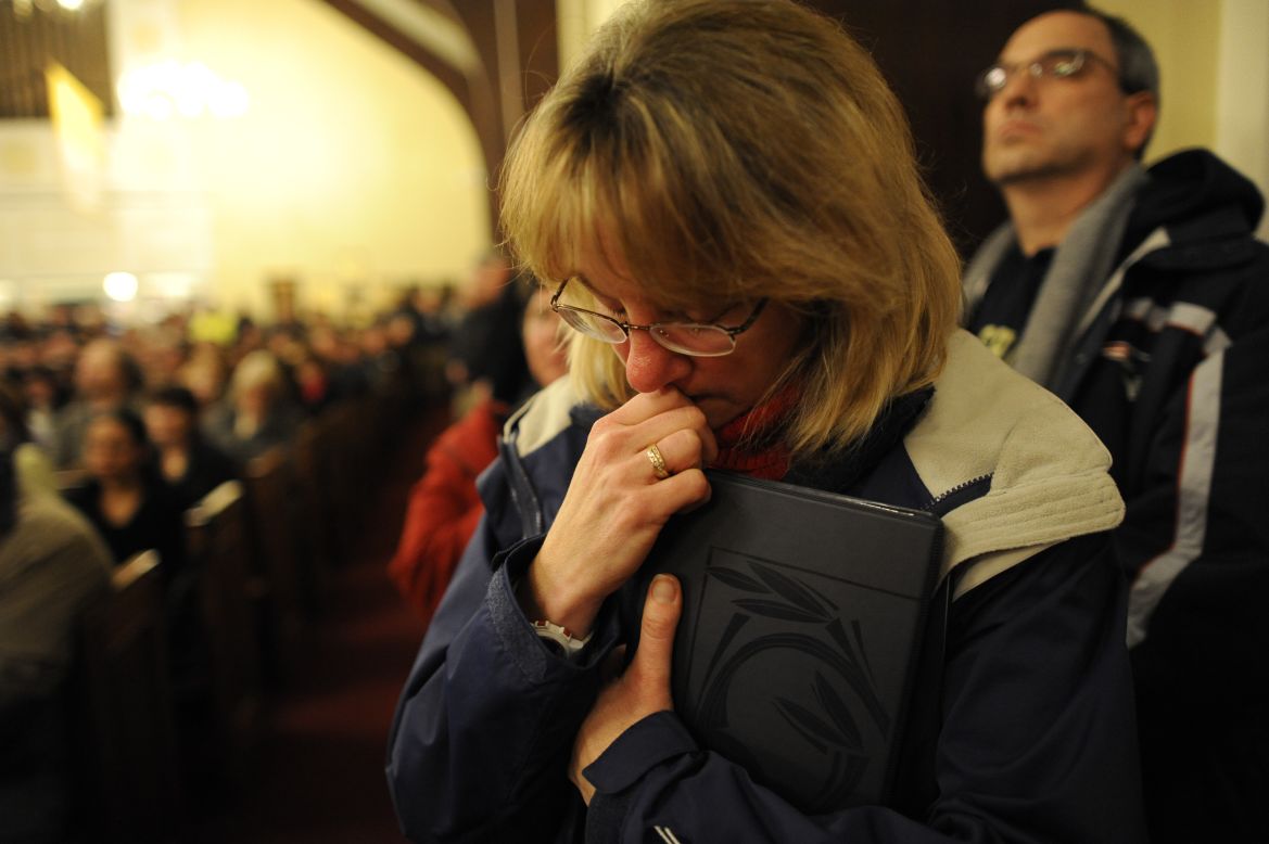 A woman bows her head during a vigil for the shooting victims at St. Rose Church.