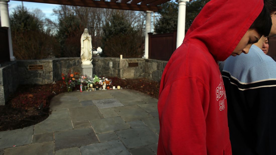 Newtown High School student Trevor Lopez stands outside of a church where residents have come to pray and reflect on Saturday