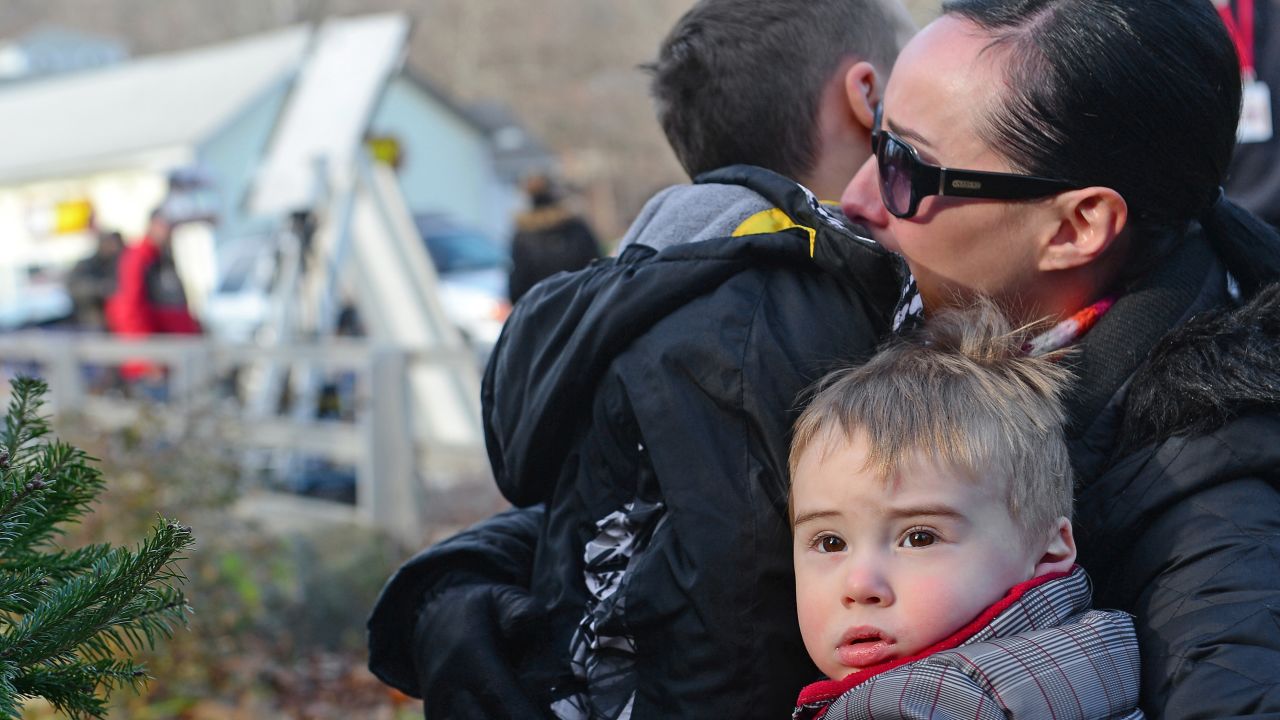A mother hugs her children after paying tribute to the victims in Newtown on Saturday, December 15.