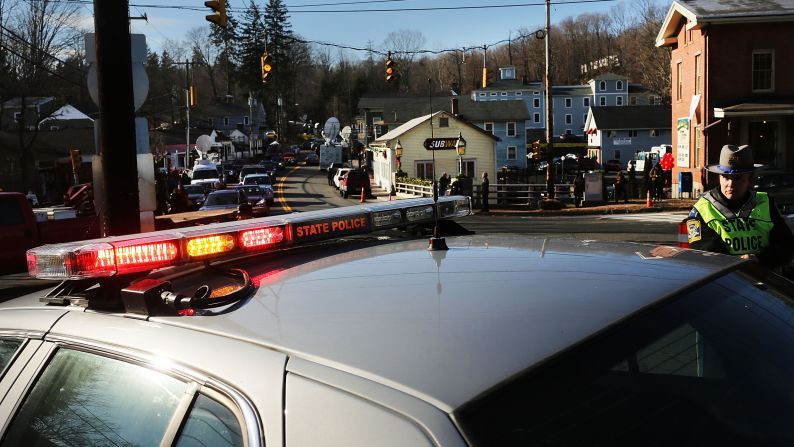 Police officers keep guard at the entrance to the street leading to the Sandy Hook Elementary School on Saturday, December 15.