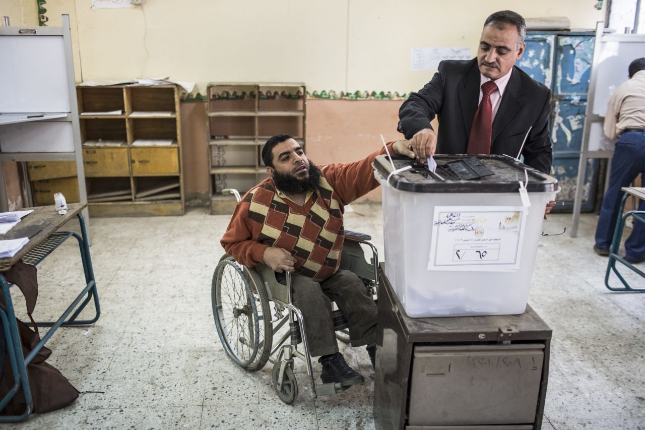 An Egyptian man receives help with dropping his vote in to a ballot box during a referendum on the new Egyptian constitution at a polling station on December 15, 2012 in Cairo, Egypt.