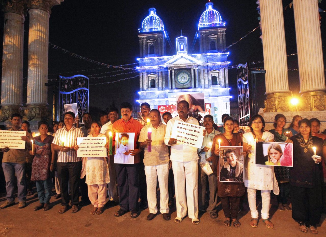 People in Bangalore, India, hold cards and photographs of the slain at a candlelight vigil outside a Catholic church on December 16.