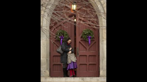 A woman hugs her daughter on the steps of Trinity Church on December 16 in Newtown.