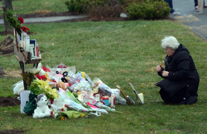 A parishioner kneels in front of a makeshift memorial at St. Rose of Lima Roman Catholic Church in Newtown on December 16.