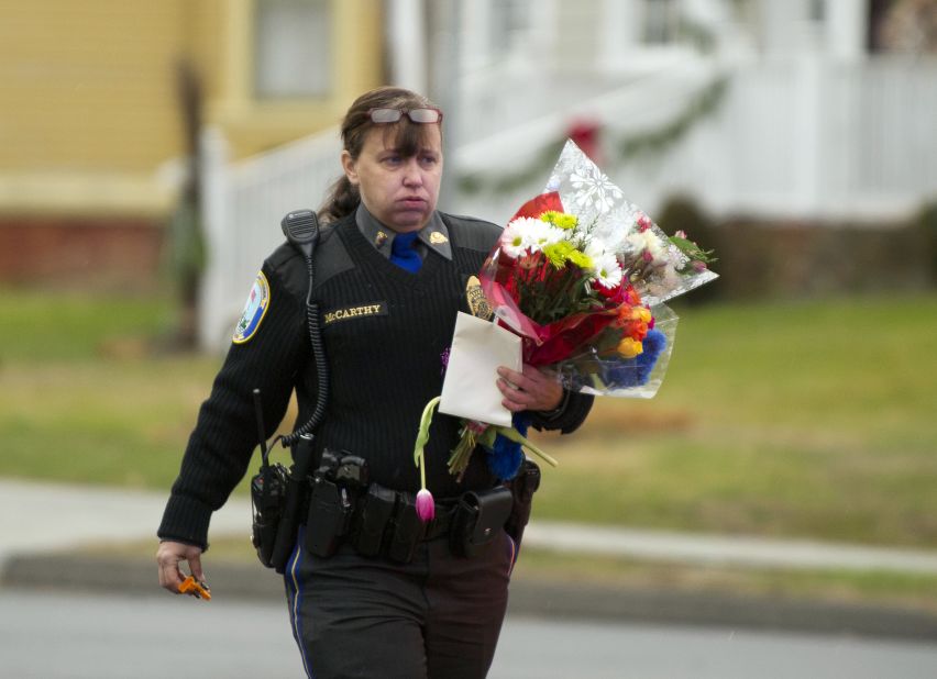 A police officer removes flowers from a busy intersection on December 16 in Newtown. Police said they were afraid the memorial, left for the victims of the Sandy Hook Elementary School shooting, would cause a traffic hazard. 