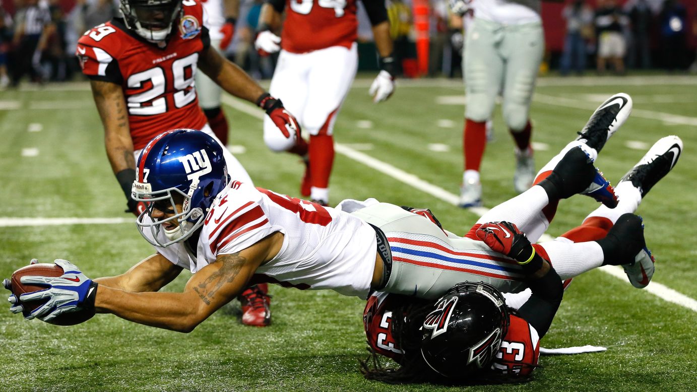 Domenik Hixon of the Giants dives for more yardage over Dunta Robinson of the Falcons on Sunday.