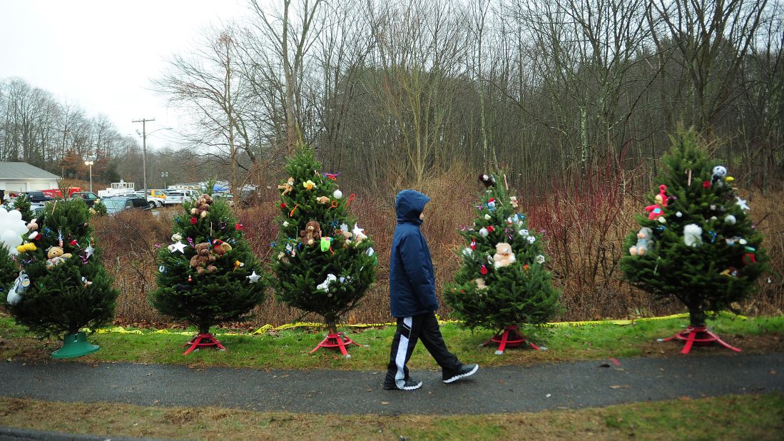 A young boy walks past Christmas trees set up at a makeshift shrine to the shooting victims in Newtown, Connecticut, on December 16.