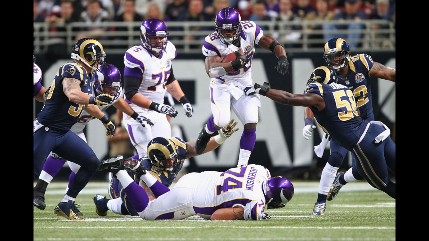 Adrian Peterson of the Vikings hurdles one of his linemen while rushing against the Rams on Sunday.