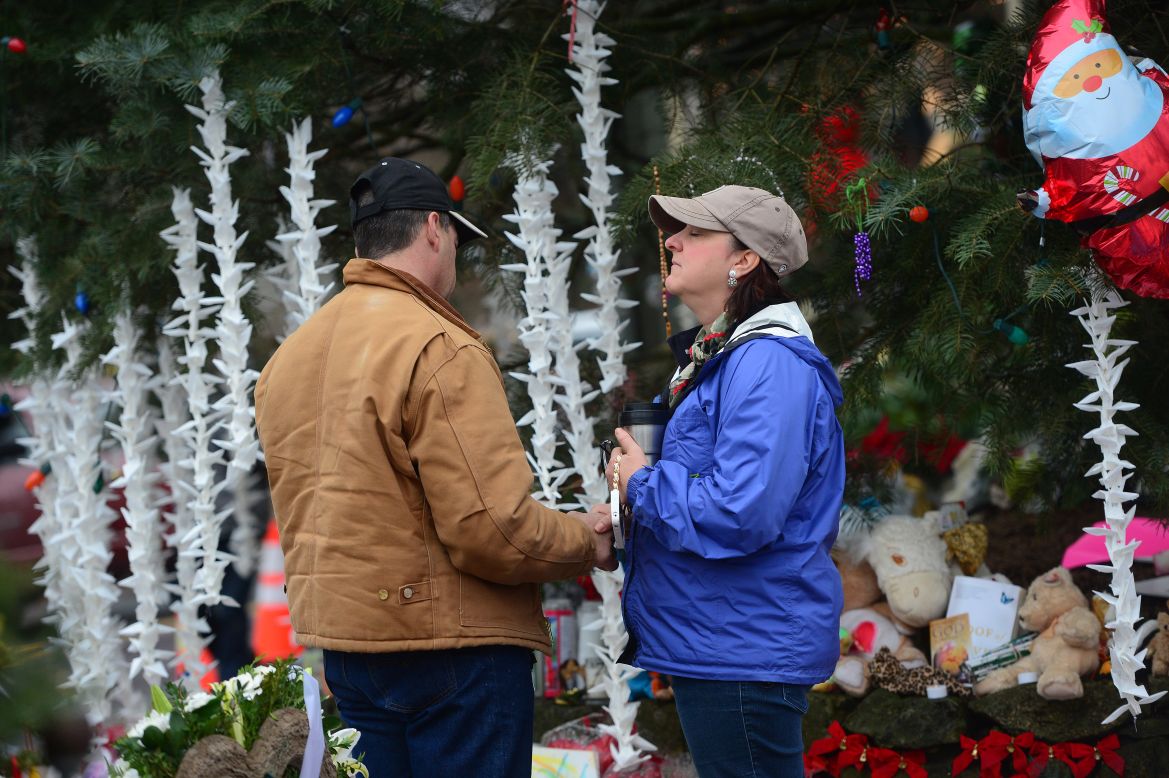 People pay their respects on December 17 at a makeshift shrine in Newtown to the victims of Friday's elementary school shooting. Funerals began Monday in the Connecticut town.