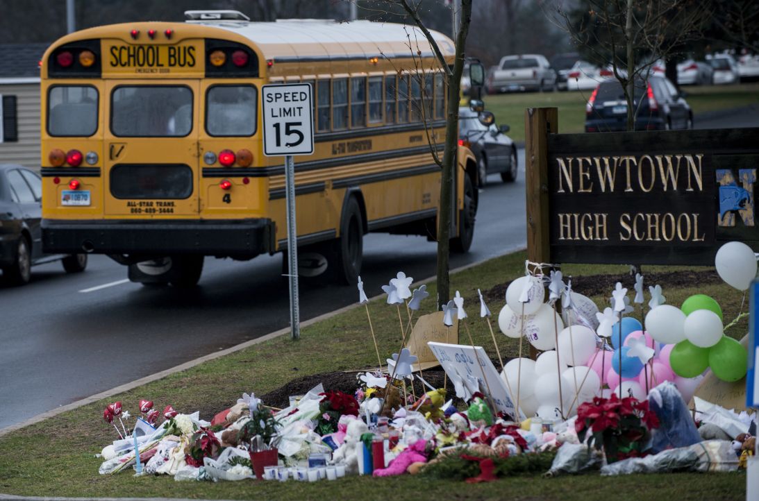 A school bus passes a makeshift memorial to the victims of the Sandy Hook Elementary School shooting as it takes students to Newtown High School December 18, 2012 in Newtown, Connecticut. Students in Newtown, excluding Sandy Hook Elementary School, return to school for the first time since last Friday's shooting at Sandy Hook