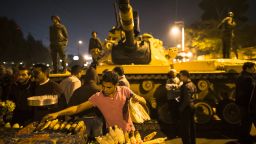 A street vendor grills corn as Egyptian soldiers stand guard at the Presidential Palace on Tuesday, December 18, in Cairo. Protesters opposed to President Mohamed Morsy's first round of voting in the constitutional referendum gather during continuing demonstrations. 