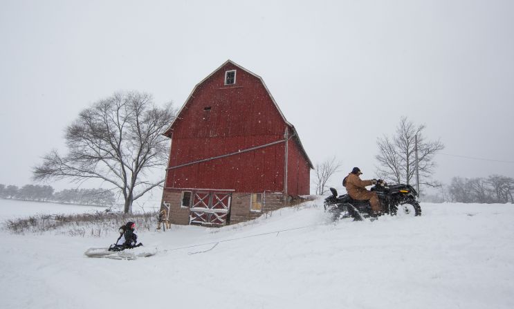 Abby Moon and Carley Moon are pulled on a mattress by their grandfather Clyde Moon's four-wheeler during a winter storm in Fairfield, Wisconsin, on Thursday, December 20.  The blizzard cut power to tens of thousands of homes and forced schools to close across the upper Midwest.