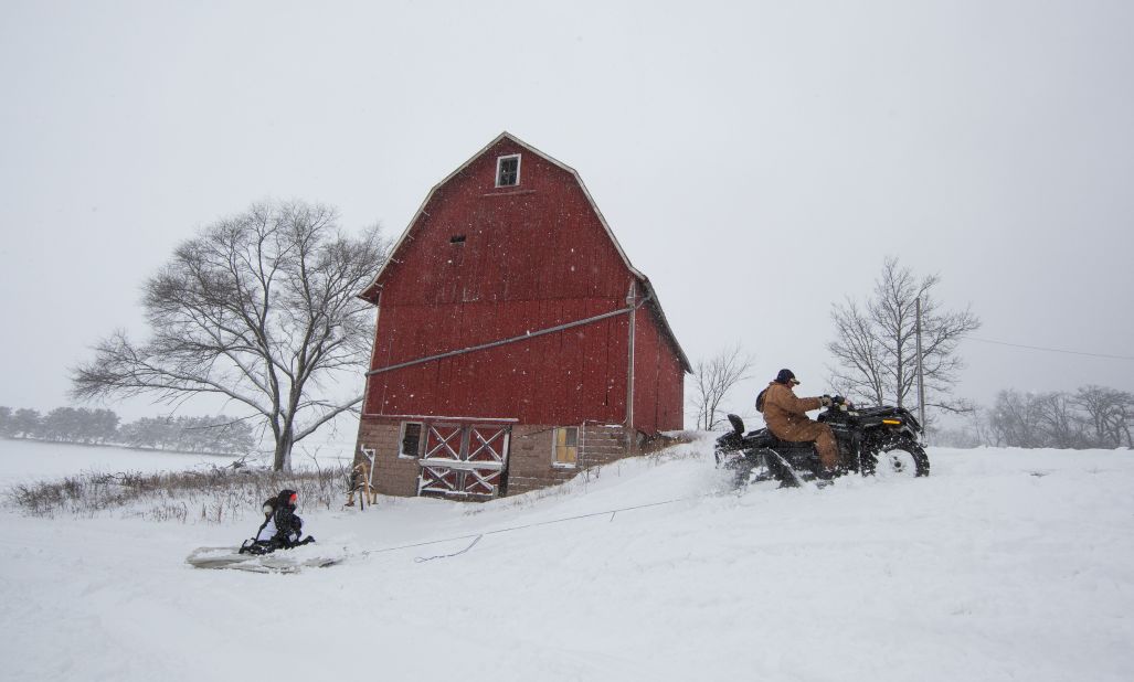 Abby Moon and Carley Moon are pulled on a mattress by their grandfather Clyde Moon's four-wheeler during a winter storm in Fairfield, Wisconsin, on Thursday, December 20.  The blizzard cut power to tens of thousands of homes and forced schools to close across the upper Midwest.