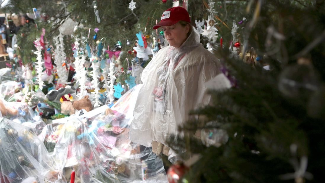A woman pauses at a streetside memorial during a moment of silence on December 21 in Newtown.
