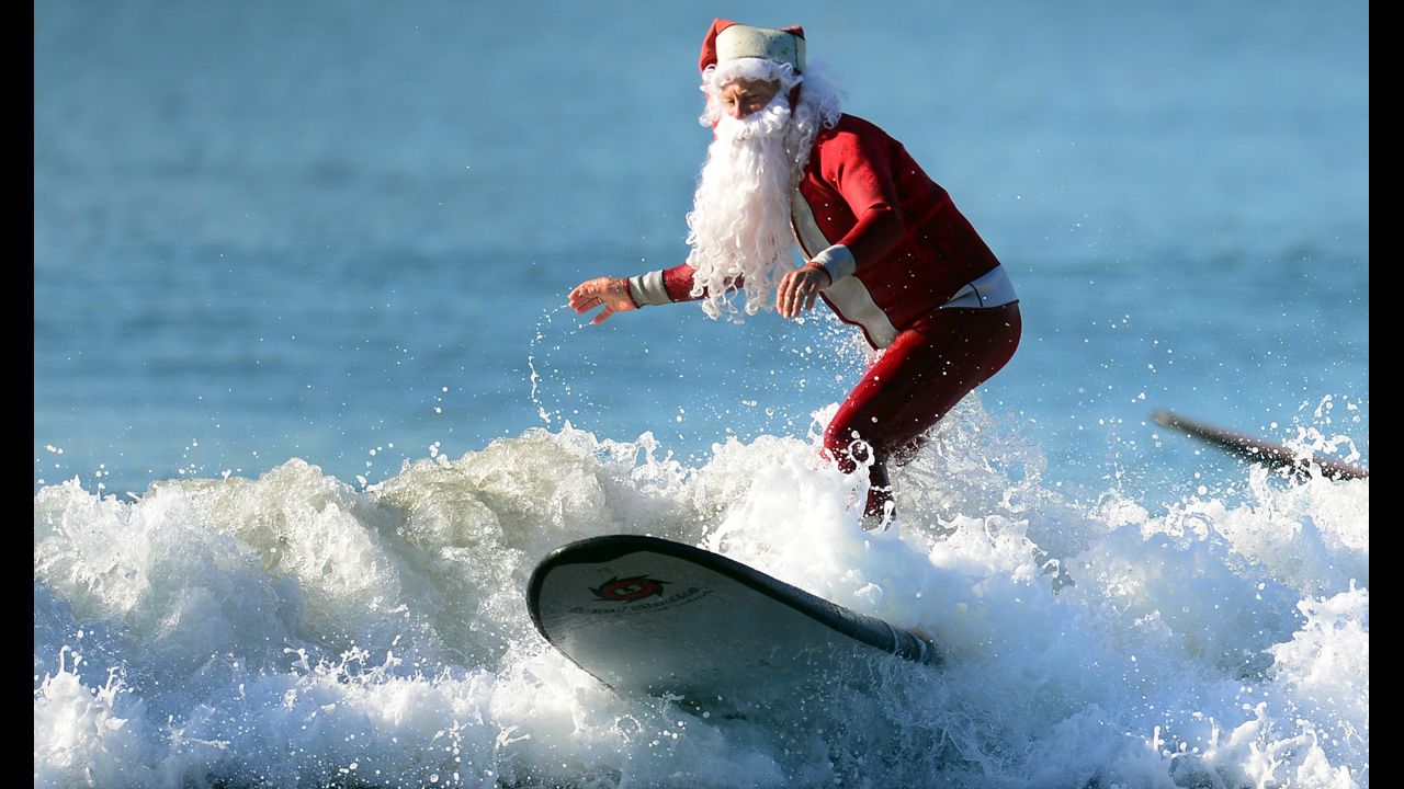 Michael Pless, 62, catches a wave off Seal Beach, south of Los Angeles, on Friday, December 21, in California. Pless, who also runs a surfing school, has been dressing up as Santa Claus and taking to the waves in costume since the 1990s, sometimes joined by his wife, Jill, in a Mrs. Claus outfit.  