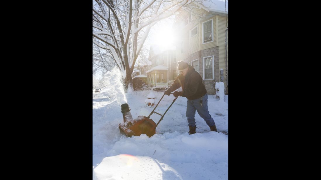 Dave Anderson uses a snow blower to clean the sidewalk in Madison, Wisconsin, on Friday.