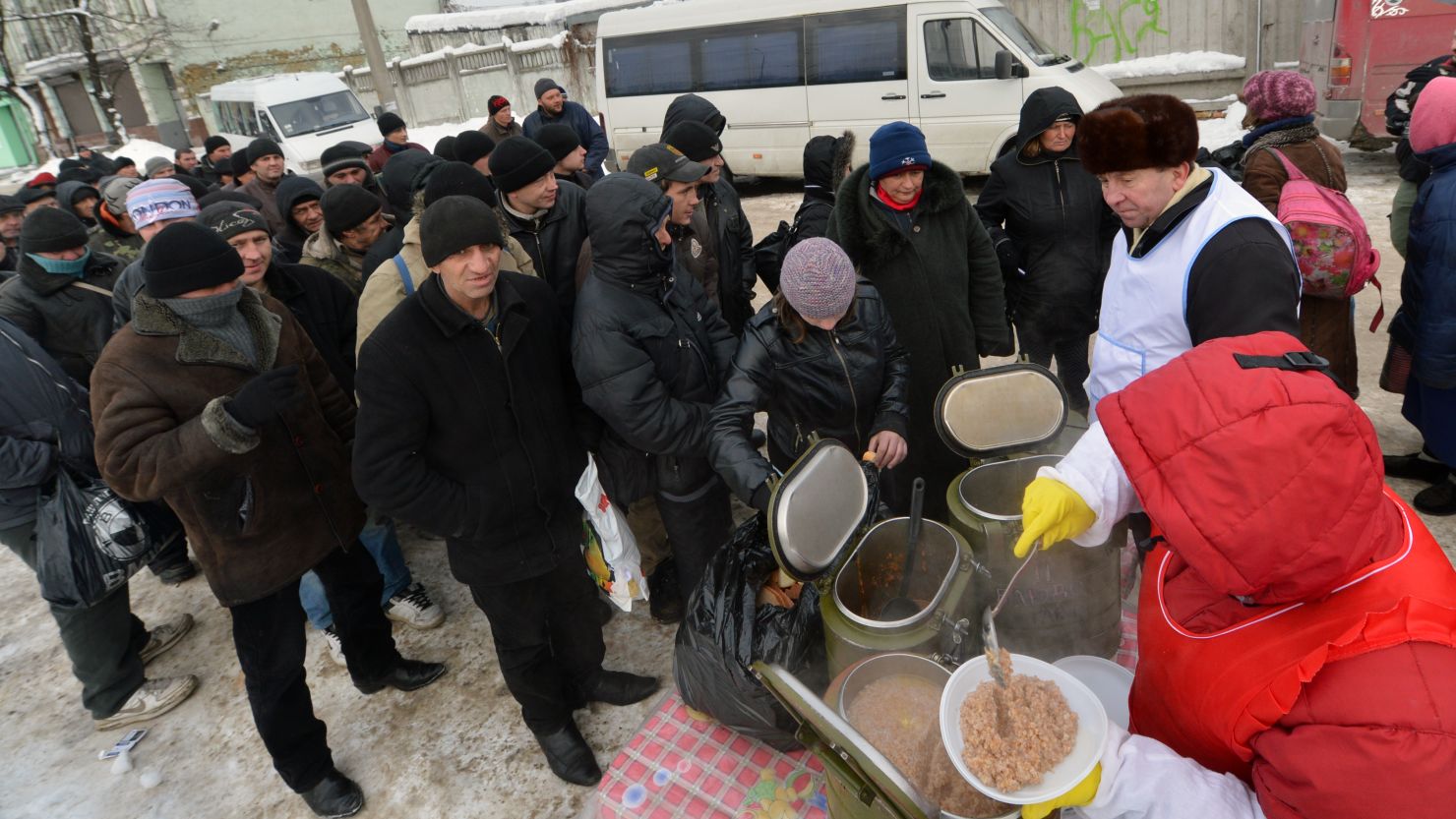Homeless people queue to get free hot food in Kiev this week as a cold snap claims many lives.