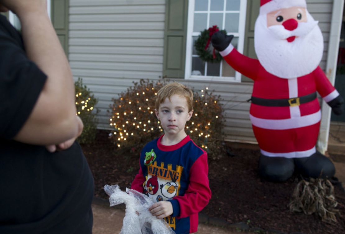 Standing with his mother, left, Chase Evans, 5, plugs in an inflatable Santa Claus at their home.