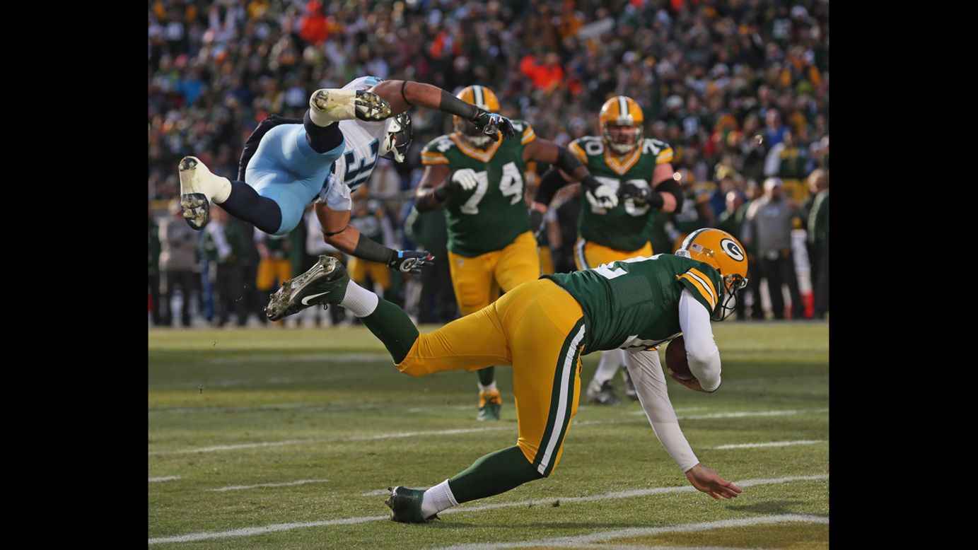 Aaron Rodgers of the Packers rolls into the end zone after being grazed by Al Afalava of the Titans on Sunday.