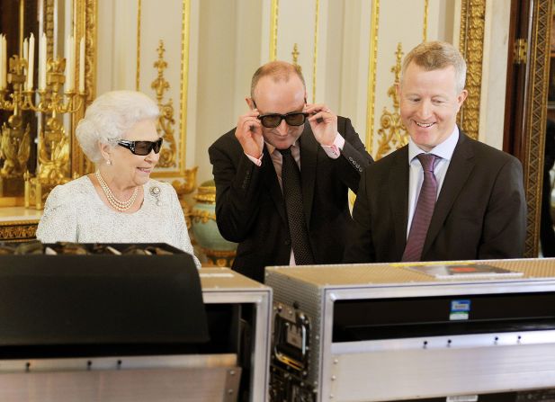Queen Elizabeth II watches the recording of her Christmas message with producer John McAndrew and director John Bennett (R). The speech will be broadcast to the Commonwealth in 3D for the first time in the White Drawing Room of Buckingham Palace.