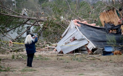 A woman takes a photo of a trailer home destroyed by a tornado near Troy, Alabama, on December 26.