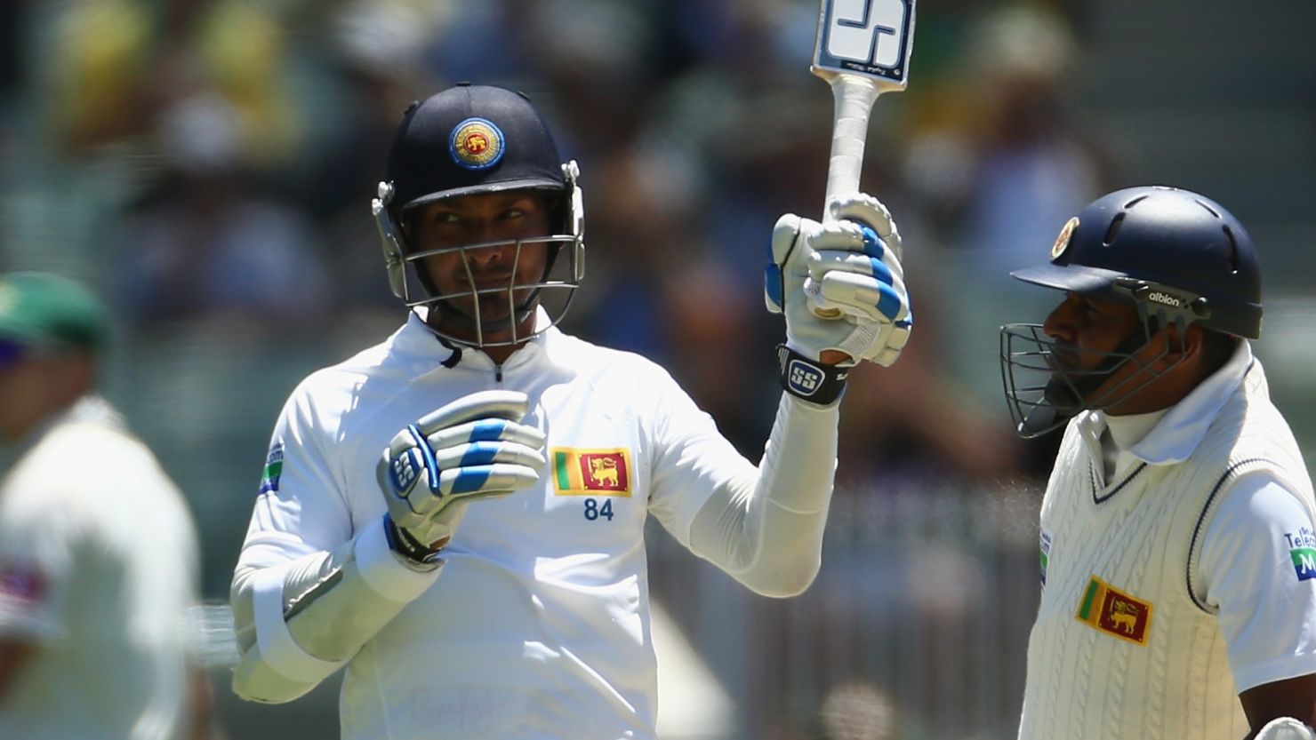 Kumar Sangakkara raises his bat after reaching 10,000 Tests in a record equaling feat.