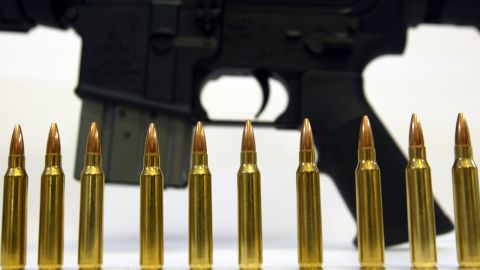 Several .223 caliber rounds near a Bushmaster XM-15; the manufacturer's owner is putting its gun companies up for sale.