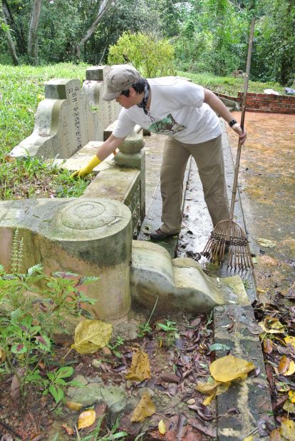 Millie Phuah clears leaves from the tomb of her great-grandparents in Bukit Brown cemetery.