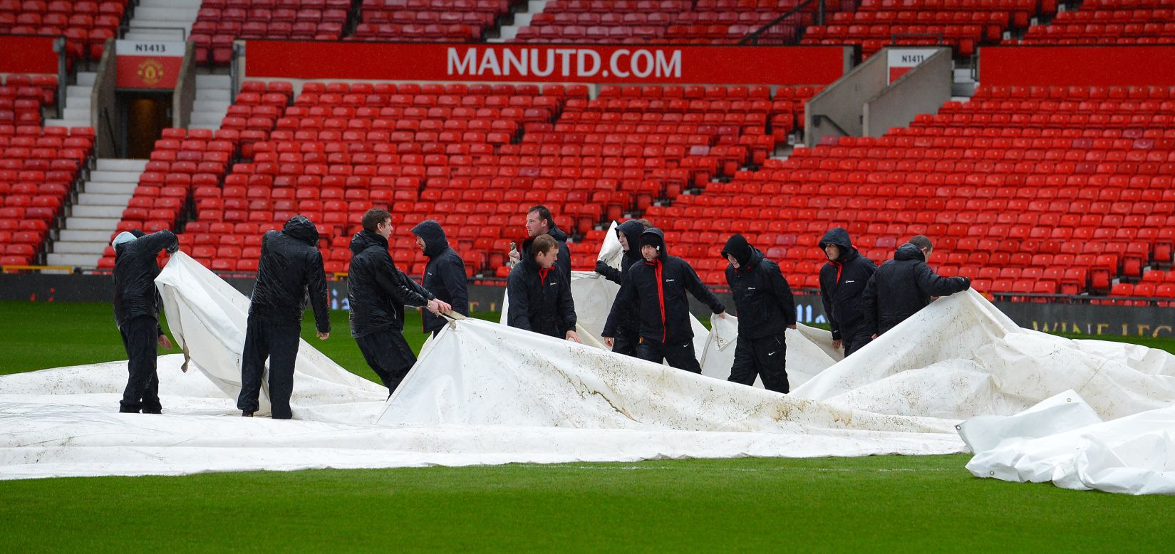 The match was cleared to go ahead after a late pitch inspection following days of rain in the UK. Groundstaff remove waterproof covers which protected the playing surface.