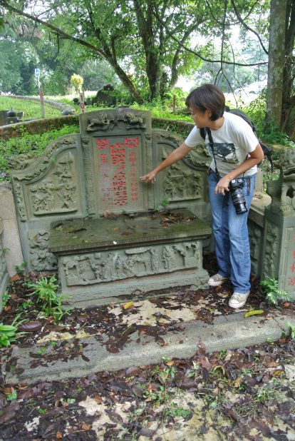 Bukit Brown supporter Claire Leow shows a tour group the grave of Tan Boon Hak.