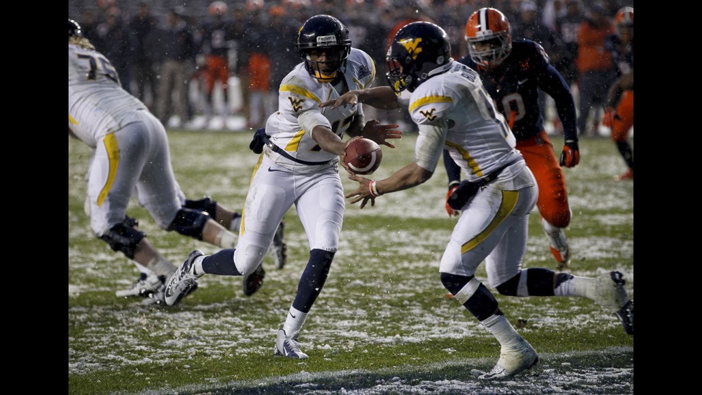 Geno Smith, left, hands off to Andrew Buie of the West Virginia Mountaineers in the New Era Pinstripe Bowl against the Syracuse Orange at Yankee Stadium on December 29 in the Bronx, New York.