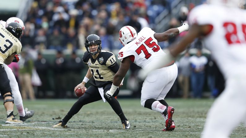 Jordan Rodgers of the Vanderbilt Commodores looks to pass the ball while under pressure from T.Y. McGill of the North Carolina State Wolfpack on December 31.