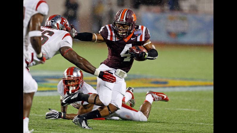 The Hokies' J.C. Coleman straight-arms Rutgers' Marvin Booker on December 28.