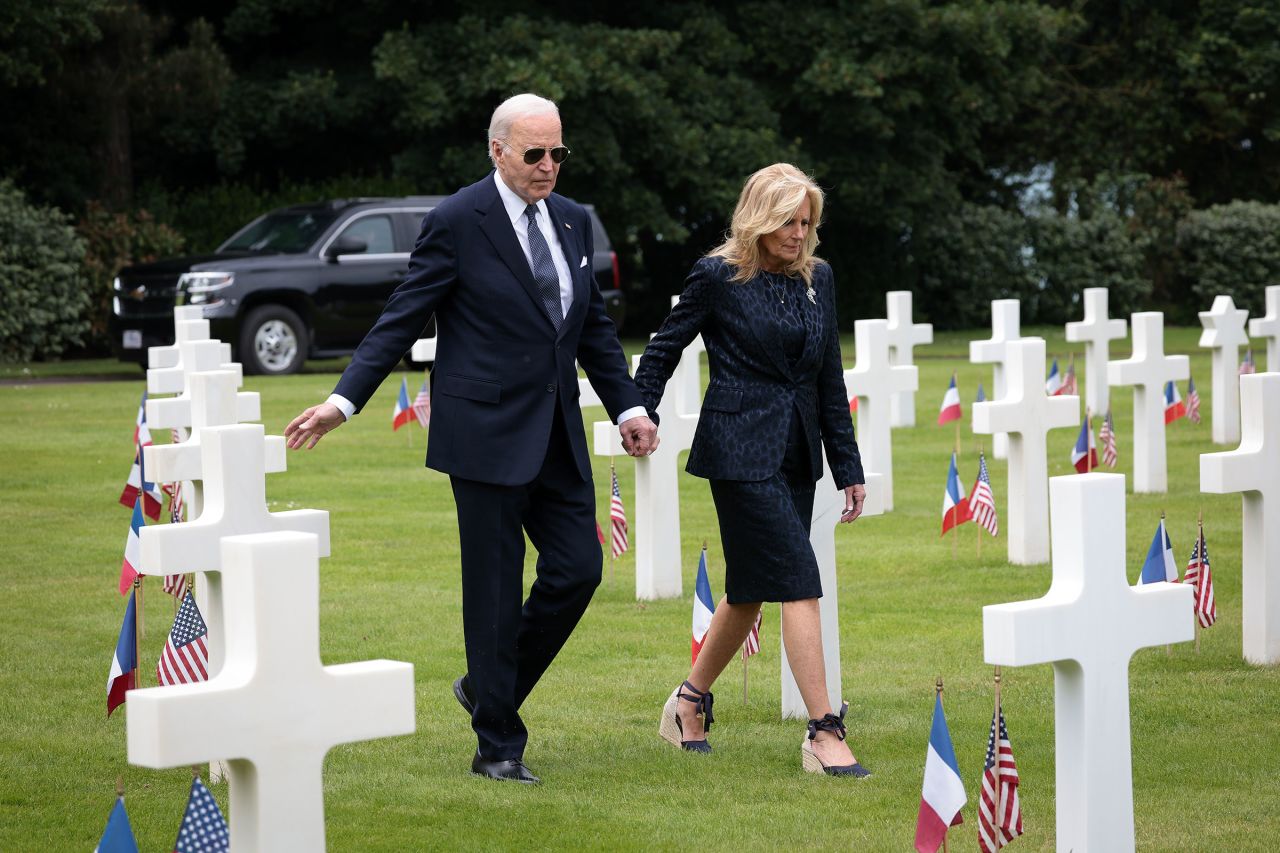 President Joe Biden reaches out to touch a US soldier's tombstone as he and first lady Jill Biden tour the Normandy American Cemetery on the 80th anniversary of D-Day on June 6, 2024 in Colleville-sur-Mer, France.