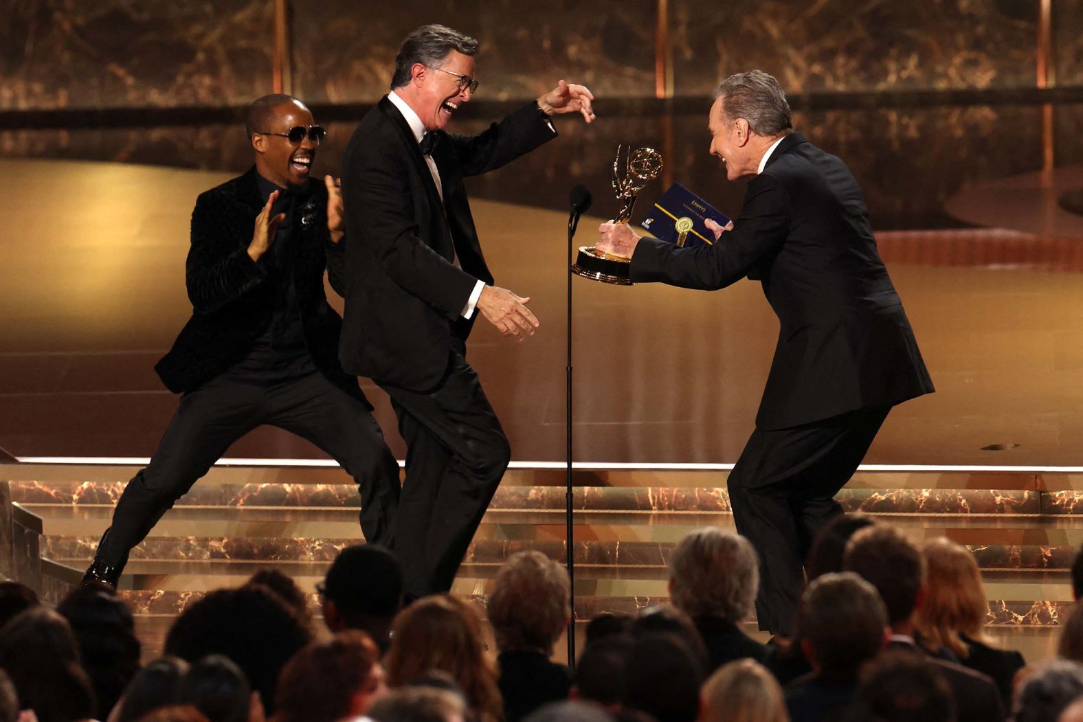 Late-night talk show host Stephen Colbert, center, accepts an Emmy Award from actor Bryan Cranston on Sunday, September 14. Colbert’s show won outstanding talk series for the first time. <a href="index.php?page=&url=https%3A%2F%2Fwww.cnn.com%2F2025%2F09%2F14%2Fentertainment%2Frecap-emmy-awards-noah-wyle">See more highlights from the Emmys</a>.
