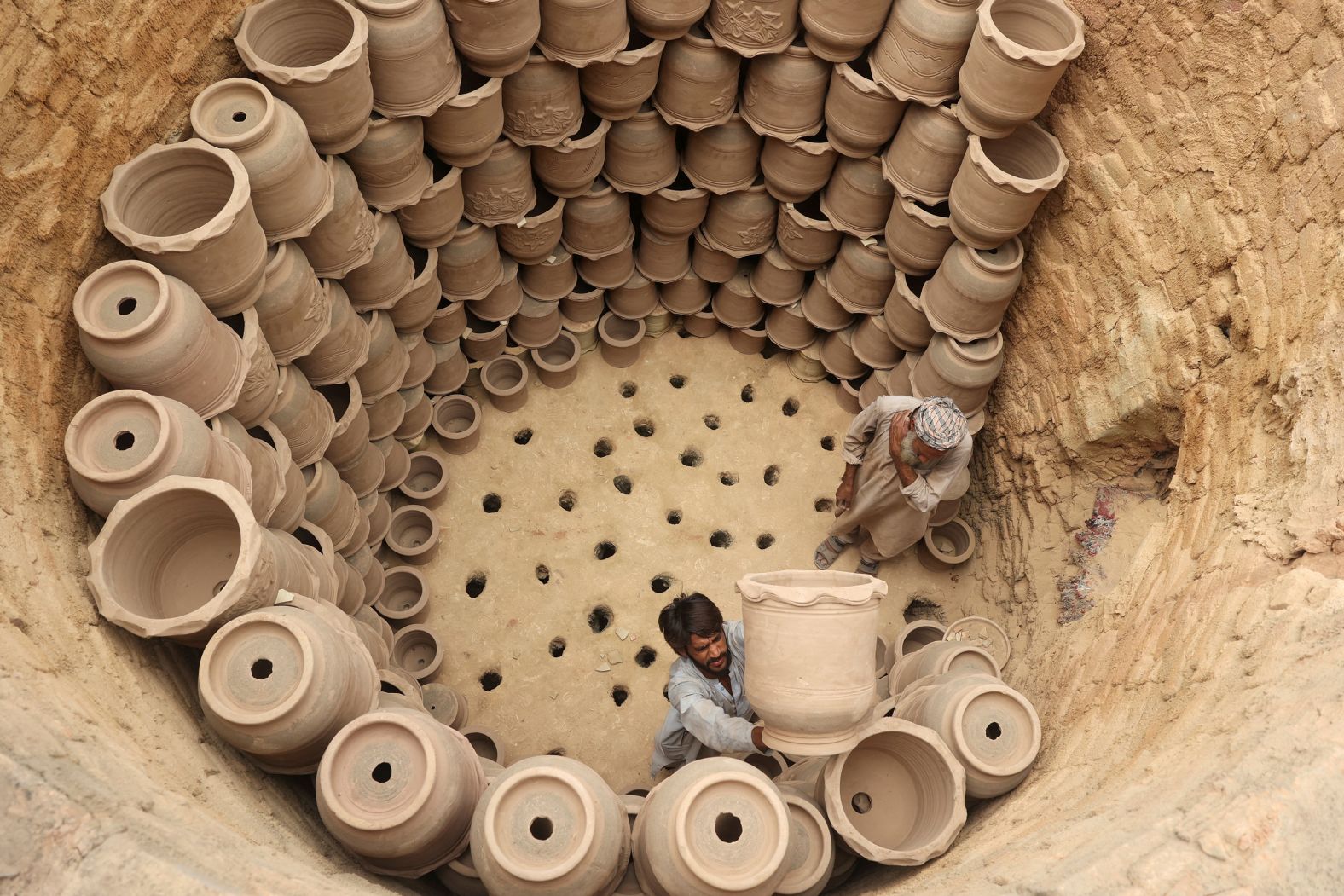 Workers arrange clay pots inside a kiln at a factory in Peshawar, Pakistan, on Wednesday, July 2.