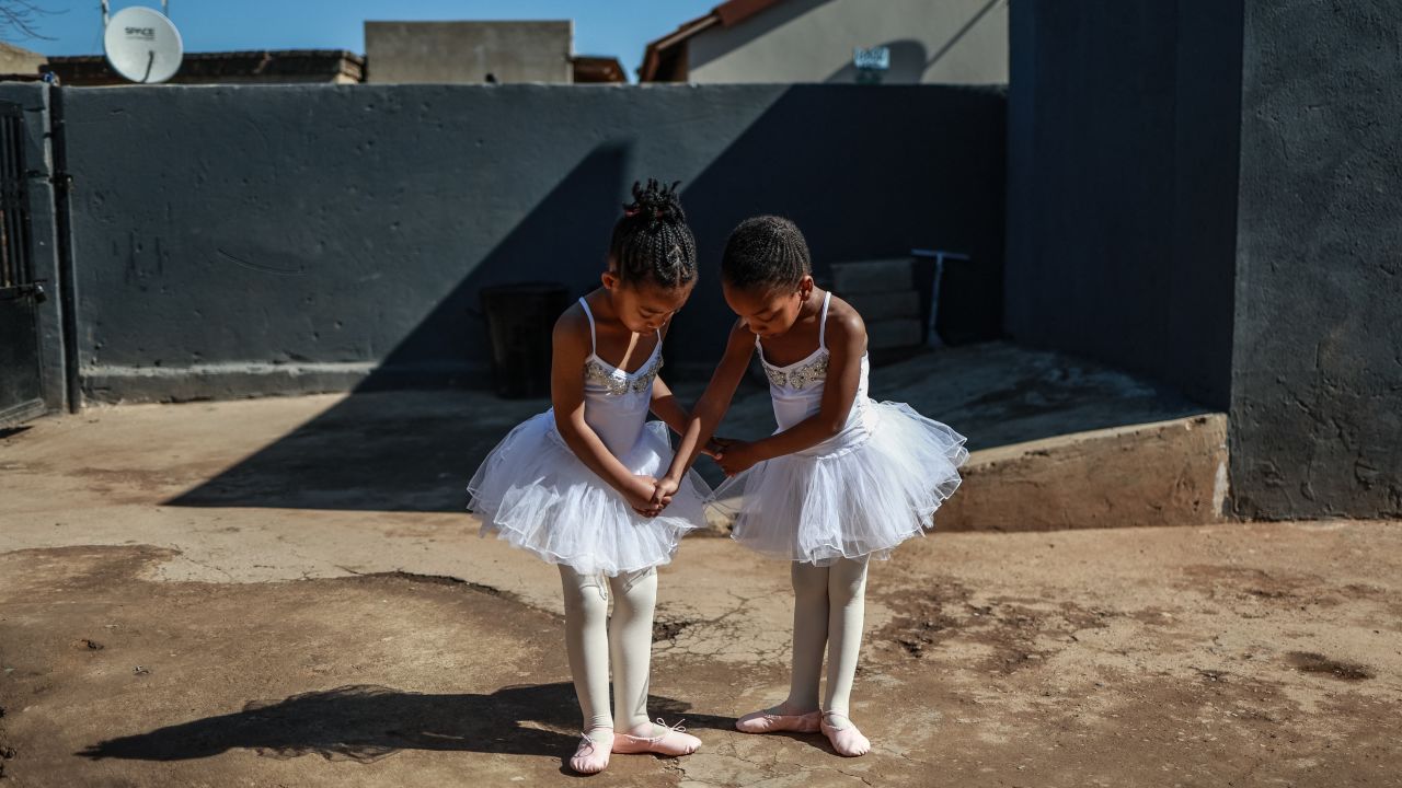 TOPSHOT - Young ballet students Philasande Ngcobo (L), 5, and Yamihle Gwababa (R), 5, pose for a photograph outside the Mballet Dance Academy in Tembisa on July 26, 2025. Mballet Dance Academy is a small, deeply rooted dance academy in Winnie Mandela's section of Tembisa township. Created not just to teach ballet but to open doors in a community where resources are few and dreams often feel out of reach. (Photo by Phill Magakoe / AFP) (Photo by PHILL MAGAKOE/AFP via Getty Images)          