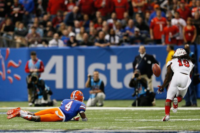 Terell Floyd of the Louisville Cardinals intercepts the ball and scores a touchdown as Andre Debose of the Florida Gators falls to the field after missing the catch in the first quarter on January 2.