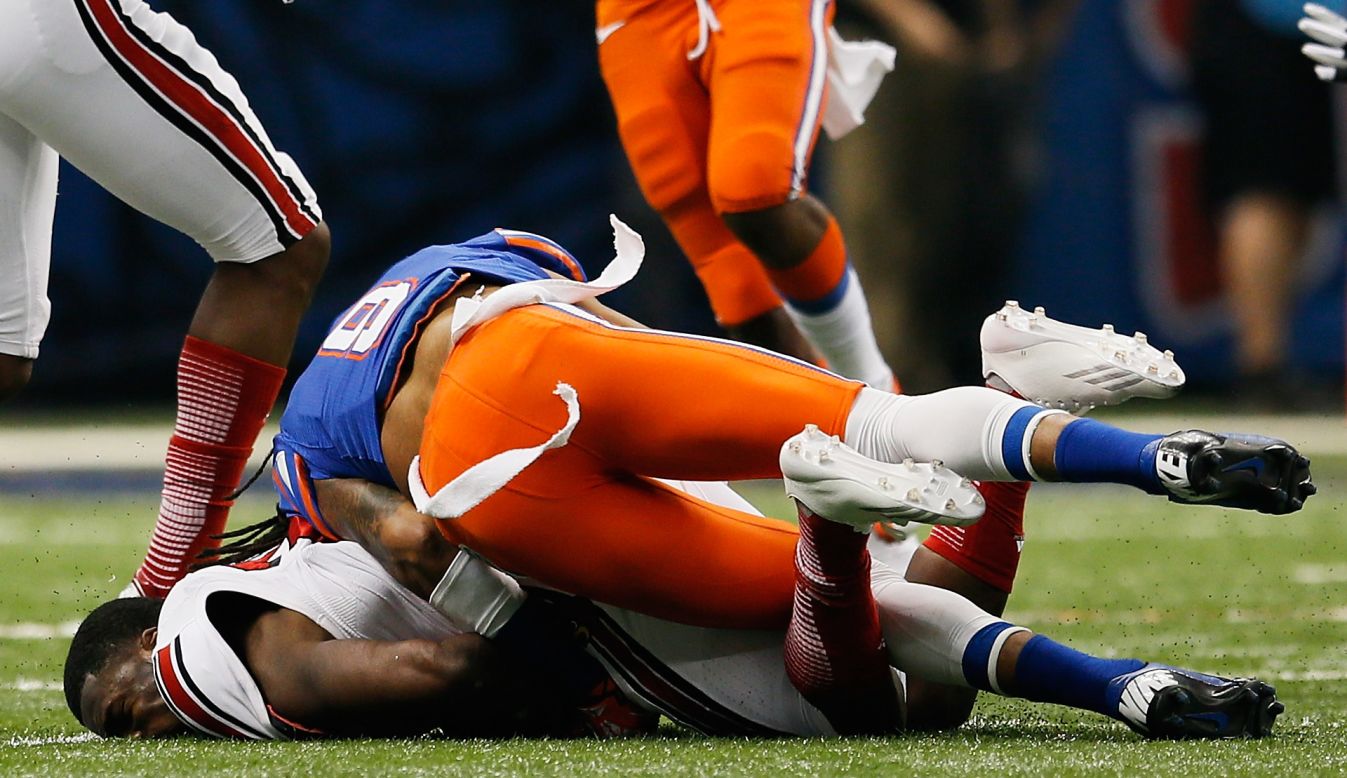Jeremy Wright of the Louisville Cardinals is tackled to the ground and loses his helmet as he is hit by Josh Evans of the Florida Gators on January 2.