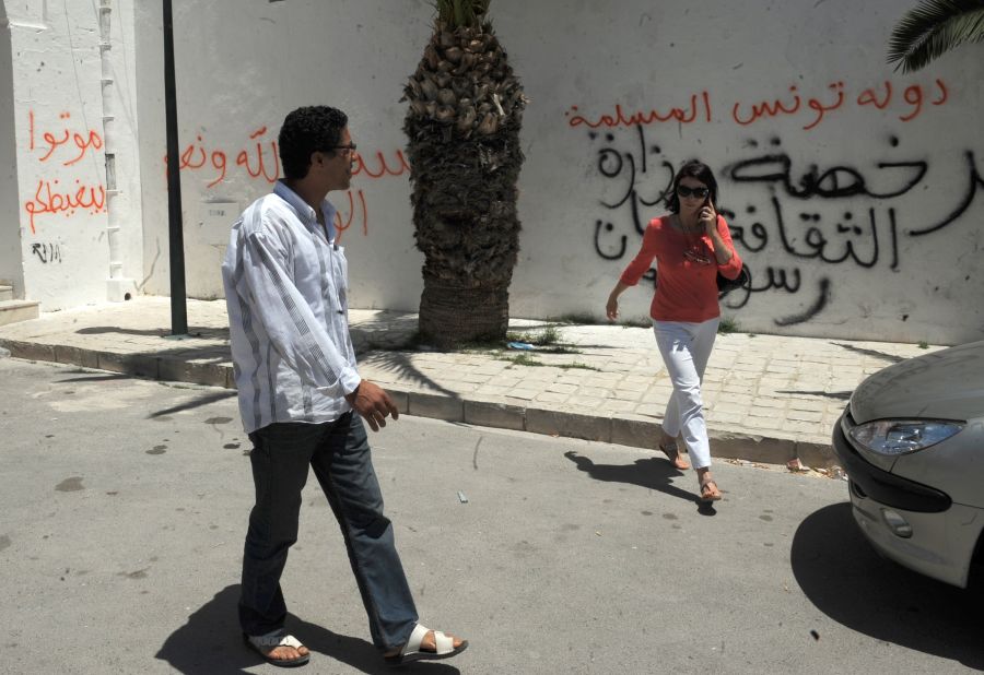 Tunis residents walk past graffiti left by rioters on a building housing a controversial art exhibition in the Tunisian capital in June 2012. The graffiti  messages read: "God is great,," "Non-believers have no place in Tunisia" and "You are enemies of God."