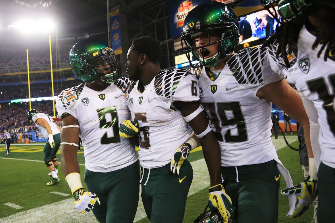 De'Anthony Thomas of the Oregon Ducks celebrates with Byron Marshall, left, and Will Murphy, right, after he returned the opening kickoff for a touchdown against the Kansas State Wildcats on January 3.